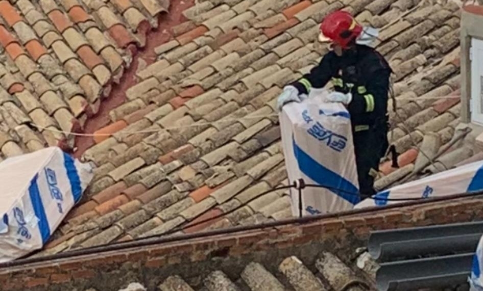 Los bomberos retiran objetos caidos en un tejado de la calle Concepción esta mañana