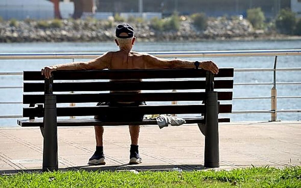 Un jubilado descansa del bochorno en un paseo de Avilés.